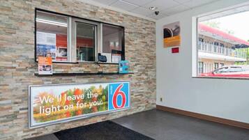 A reception area with a stone wall, a window, a counter with a computer, and a large sign with the number 6.