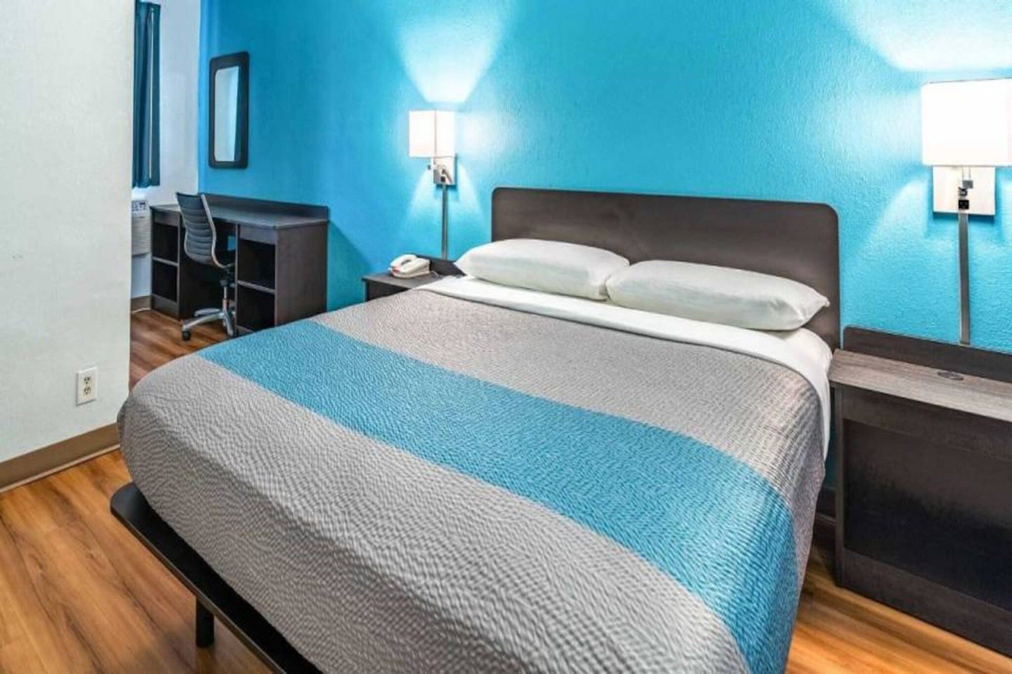 Una habitación de hotel con cama, escritorio y silla.