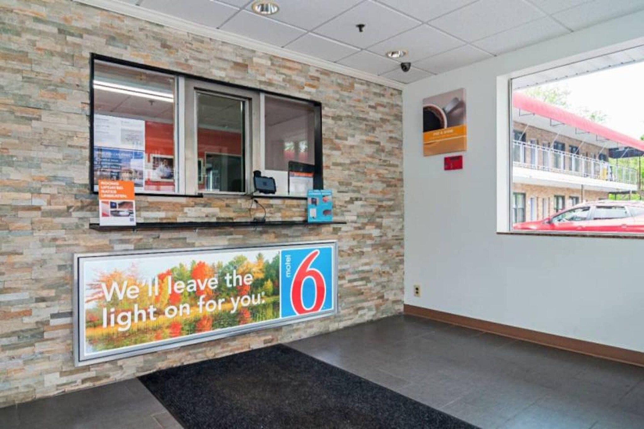 Zona de recepción con pared de piedra, una ventana, mostrador con computadora y un cartel grande con el número 6.