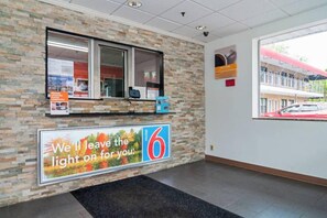 Zona de recepció amb pared de pedra, una finestra, mostrador amb un ordinador i un cartell gran amb el número 6.