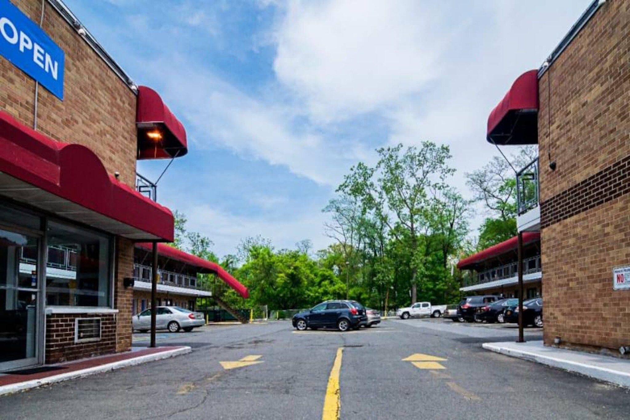 A parking lot with cars, a building with a red awning, and a clear sky.