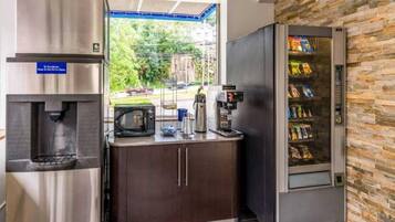 A kitchenette with a water dispenser, microwave, coffee machine, and snack vending machine.
