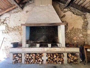 A stone fireplace with a chimney, surrounded by stacked firewood. - Large property with privacy and private pool (La Chapelle-Grésignac)