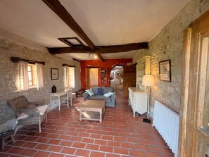 A rustic interior with a brick floor, a sofa, a table, and a radiator. - Large property with privacy and private pool (La Chapelle-Grésignac)