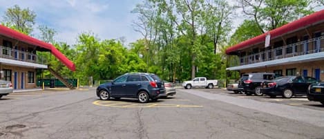 A parking lot with multiple cars, a building with red awnings, and trees in the background.