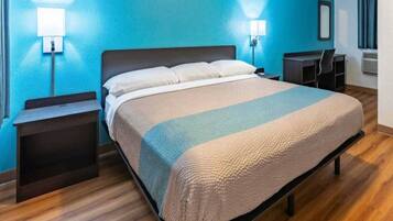 Une chambre d’hôtel avec un lit, des tables de chevet, un bureau et une chaise.