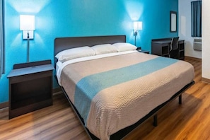Une chambre d’hôtel avec un lit, des tables de chevet, un bureau et une chaise.