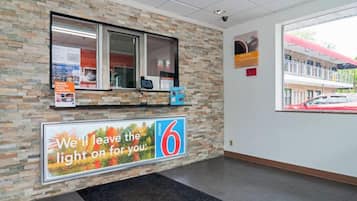 Une salle d’accueil avec un mur en pierre, une fenêtre, un comptoir avec un ordinateur et un grand panneau indiquant le numéro 6.