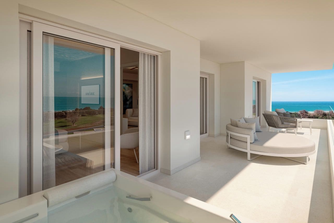 Un interior moderno con un ventanal de vidrio que da a un balcón con vistas al mar.