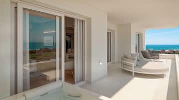 Un interior moderno con un ventanal de vidrio que da a un balcón con vistas al mar.