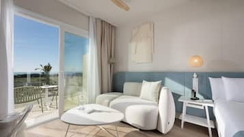 Una habitación de hotel moderna con balcón, sofá, pequeña mesa y cama.