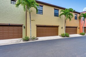 A row of residential buildings with garage doors, palm trees, and a clear sky. - Olé at Lely Resort, More Than a Vacation (Naples)