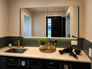 Ein modernes Badezimmer mit Waschbecken, Spiegel und einem Hisense Geschirrspüler darunter.