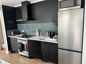 Ett modernt kök med ett kylskåp i rostfritt stål, en inbyggd ugn och en mikrovågsugn.