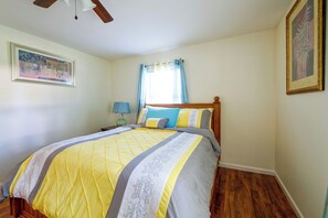 A bedroom with a bed, a nightstand, a lamp, a ceiling fan, and a window with curtains. - Walk to Dining: Relax at 609 Gray (Wildwood)