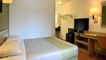 A hotel room with a bed, a desk, a television, and a microwave.