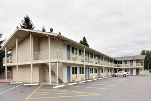 Ein Motel mit zweistöckiger Struktur, einem überdachten Parkbereich und einem anliegenden eingeschossigen Gebäude.