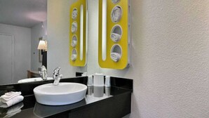 Un baño con un lavamanos blanco, un espejo y un toallero amarillo con varios espacios.