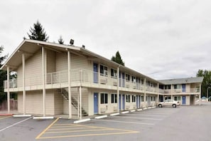 Ein Motel mit zweistöckiger Struktur, einem überdachten Parkbereich und einem anliegenden eingeschossigen Gebäude.