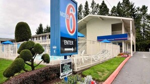 Un motel con un letrero azul llamativo que indica el nombre y una flecha que señala la entrada.