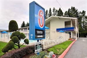 Ein Motel mit einem auffälligen, blauen Schild, das den Namen anzeigt und einen Pfeil zum Eingang weist.