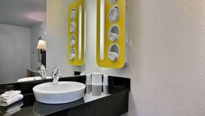 Un baño con un lavabo blanco, un espejo y un perchero con varias toallas.