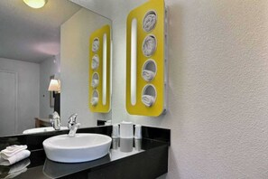 Ein Badezimmer mit einem weißen Waschbecken, einem Spiegel und einem Handtuchhalter mit mehreren Handtüchern.