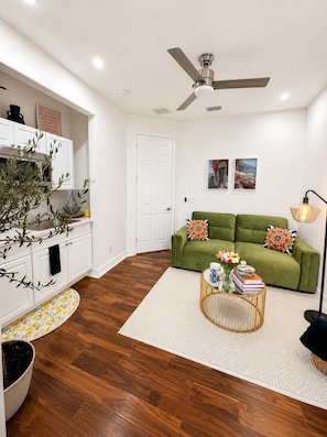 A modern living room with a green sofa, a white door, and a ceiling fan. - Peaceful studio with AC in charming Cape Coral & seasonal pool and jacuzzi (Cape Coral)
