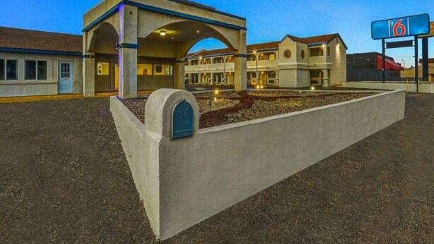 A hotel with a large parking lot, a covered entrance, and a sign indicating the number 6. - 2 Queen Beds | Non-Smoking (Clovis NM)