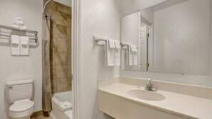 A bathroom with a toilet, a bathtub, and a sink with a mirror. - 2 Queen Beds | Non-Smoking (Clovis NM)