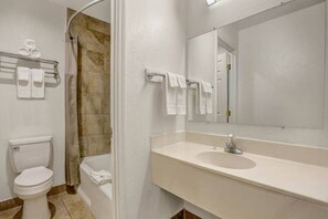 A bathroom with a toilet, a bathtub, and a sink with a mirror. - 2 Queen Beds | Non-Smoking (Clovis NM)