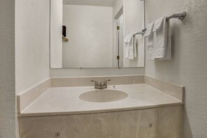 Ein Badezimmer mit einem weißen Waschbecken, einem Spiegel und einem Handtuchhalter.