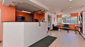 A reception area with a counter, seating, and a large window. - 1 King Bed | Smoking (RICHBURG)