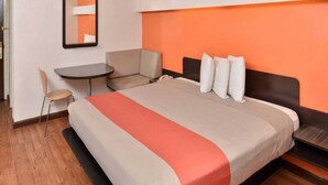 A hotel room with a bed, a desk, and a chair. - 1 King Bed | Smoking (RICHBURG)