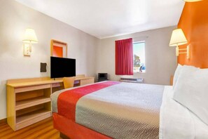 Une chambre d’hôtel avec un lit, un bureau, une télévision et une fenêtre avec des rideaux.