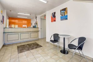 Een receptie met een balie, twee stoelen en een kleine tafel.