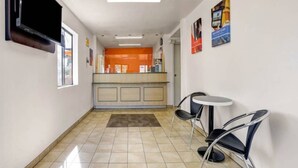 Corredor com balcão de recepção, cadeiras e piso ladrilhado.