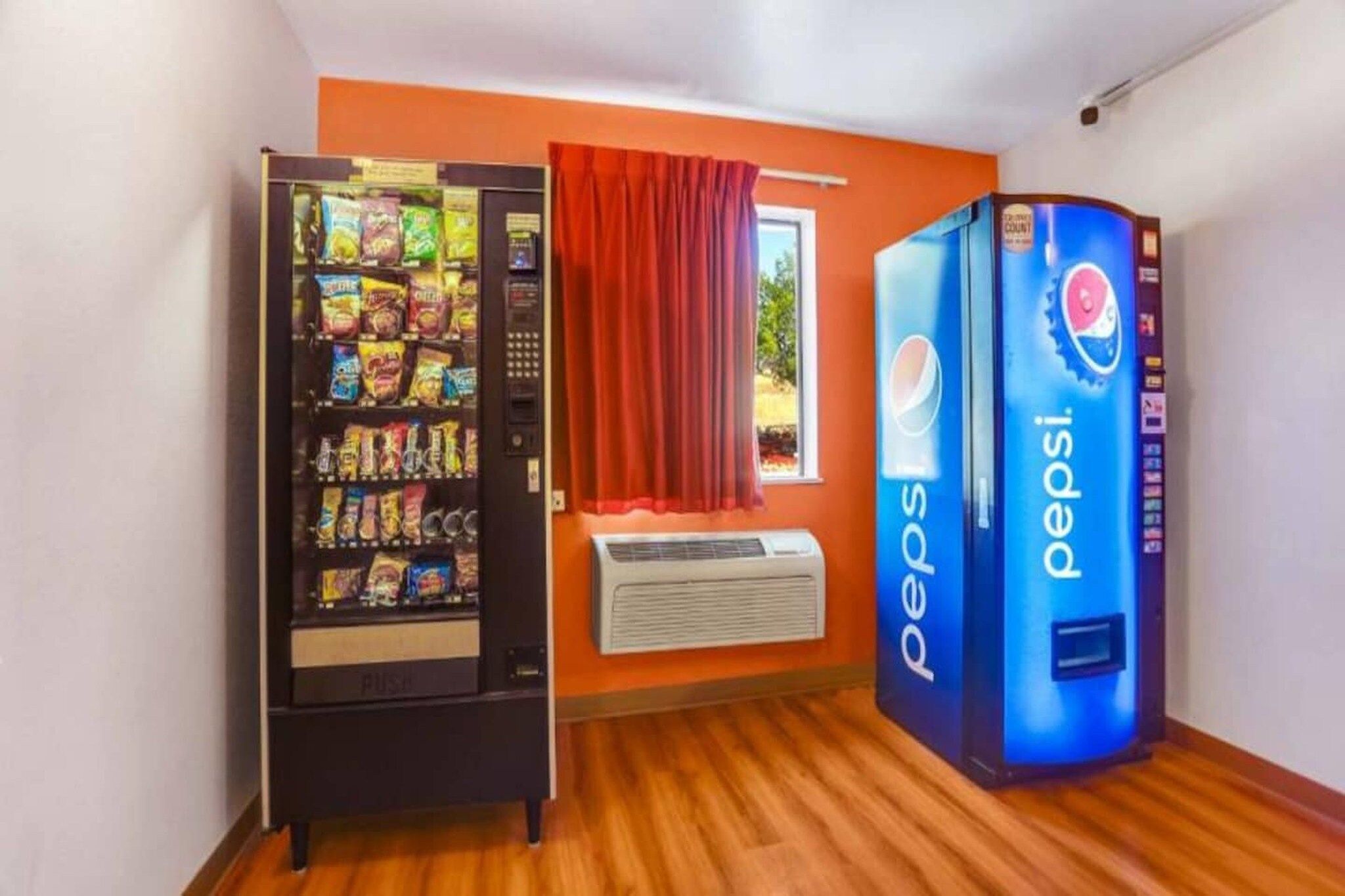 Ein Zimmer mit einem Getränkeautomaten, gefüllt mit Snacks und einem Pepsi-Kühler.