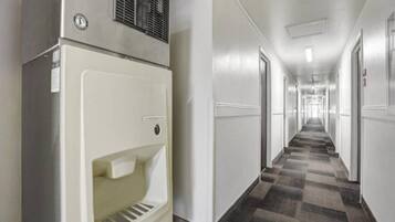 A hotel corridor with a refrigerator, doors, and a patterned carpet.