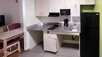 Una cocina compacta con microondas, cafetera y refrigerador.
