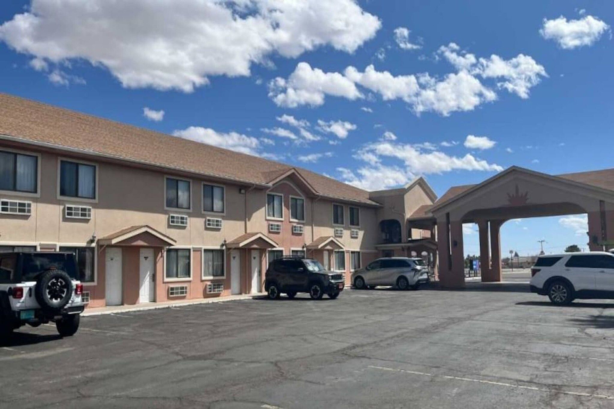 Un motel comprenant plusieurs chambres, une station-service et un parking.