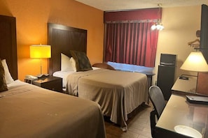 Una camera d'albergo con due letti, una scrivania, una sedia, una lampada, una televisione e un armadio.