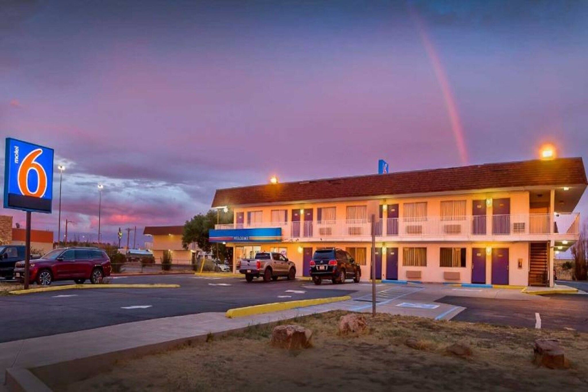 A motel with a large sign, multiple parking spaces, and a building with a flat roof.
