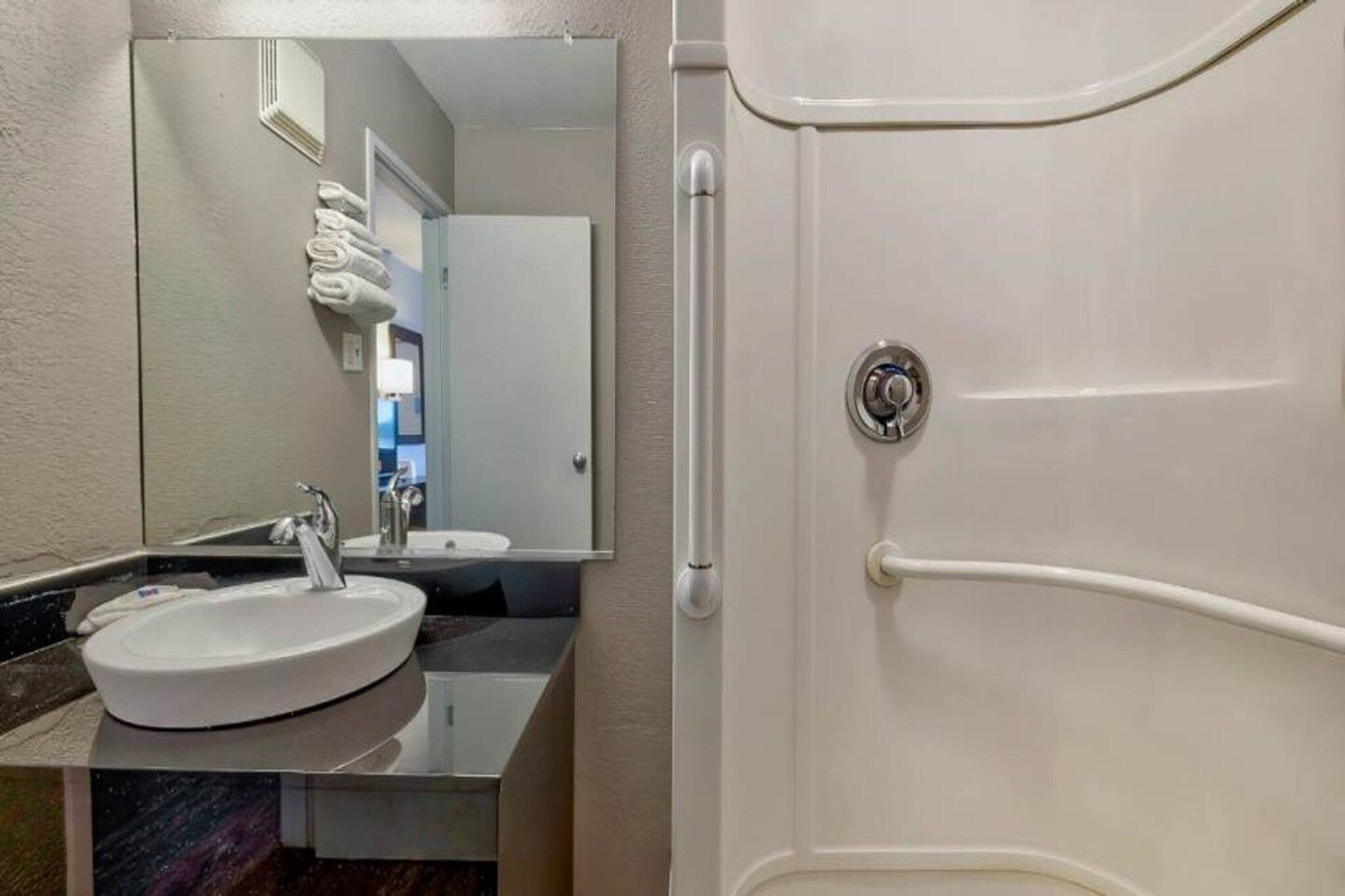 A bathroom with a sink, mirror, and a shower door.