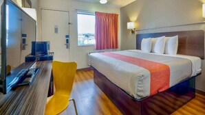 A hotel room with a bed, a desk with a computer, a chair, and a window with curtains. - 1 Queen Bed|ADA/RI Shower (Santa Rosa NM)