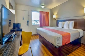 A hotel room with a bed, a desk with a computer, a chair, and a window with curtains. - 1 Queen Bed|ADA/RI Shower (Santa Rosa NM)