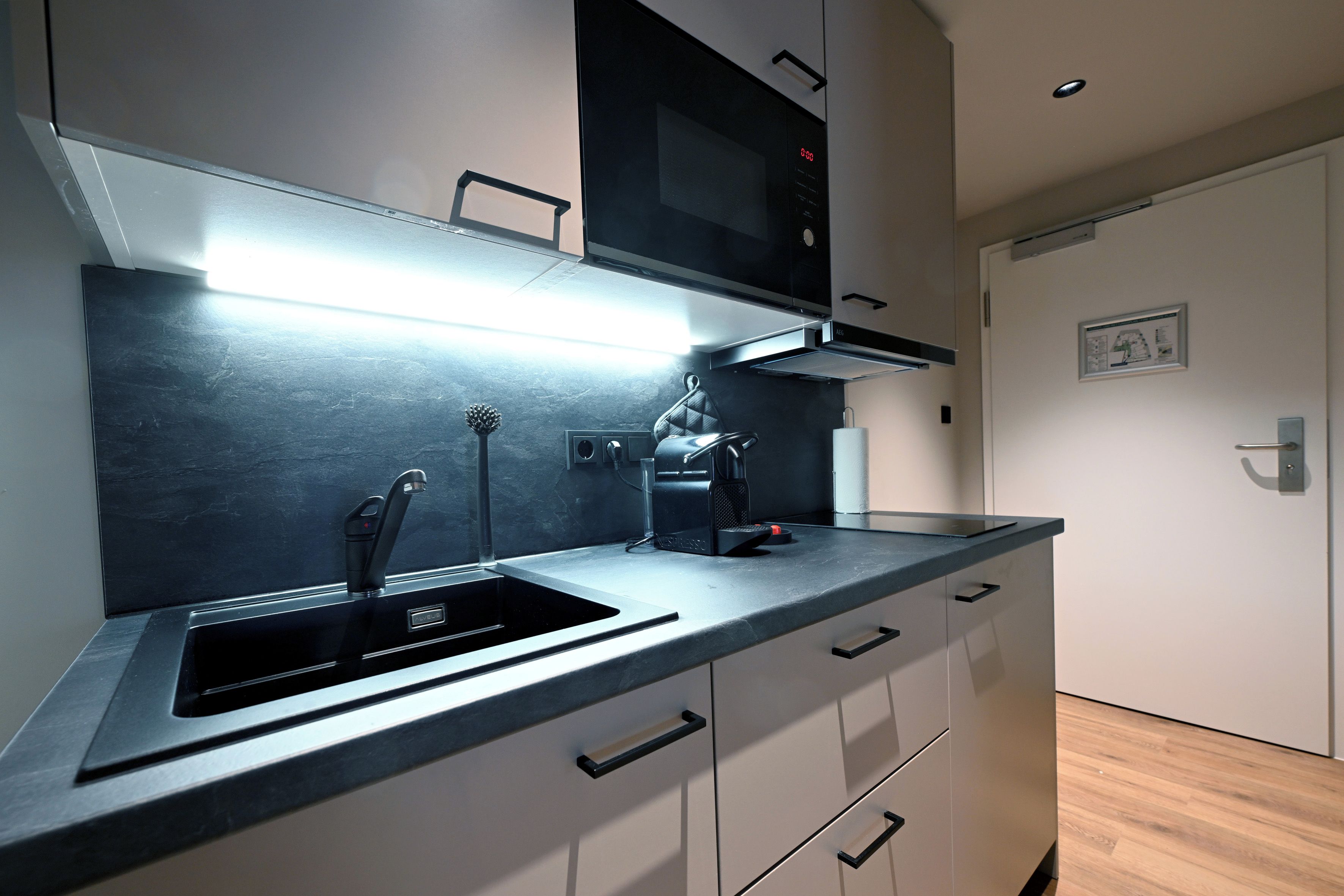 Una cocina moderna con un lavamanos empotrado, un microondas y una cafetera.