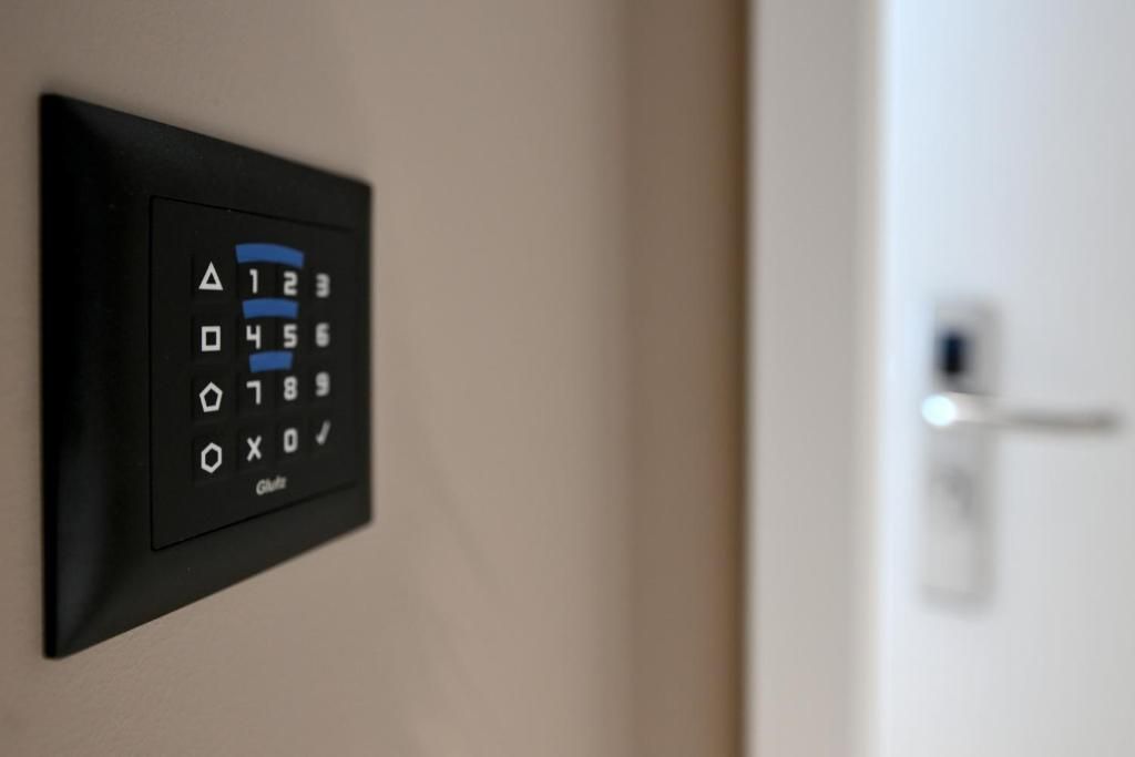 A wall-mounted electronic keypad, likely for room access, with a door visible in the background.