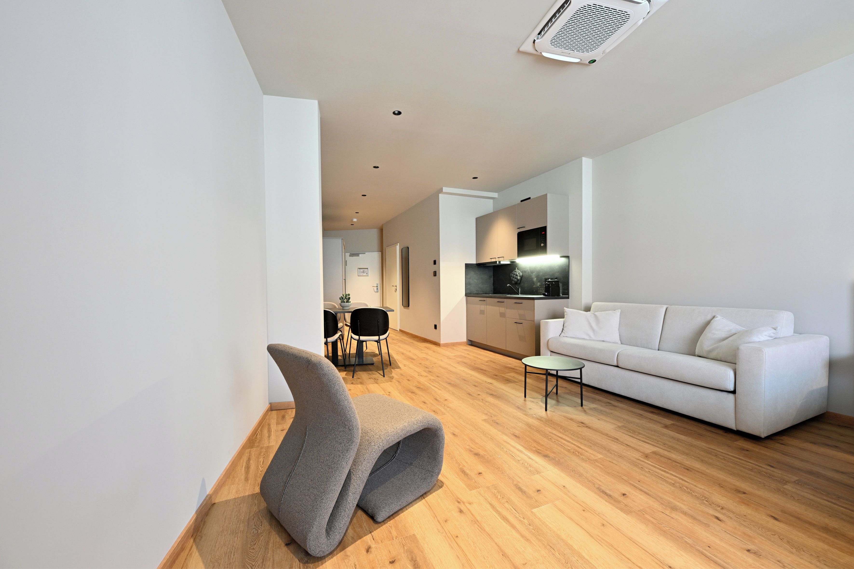 A modern living room with a white sofa, a grey chair, and a small table.