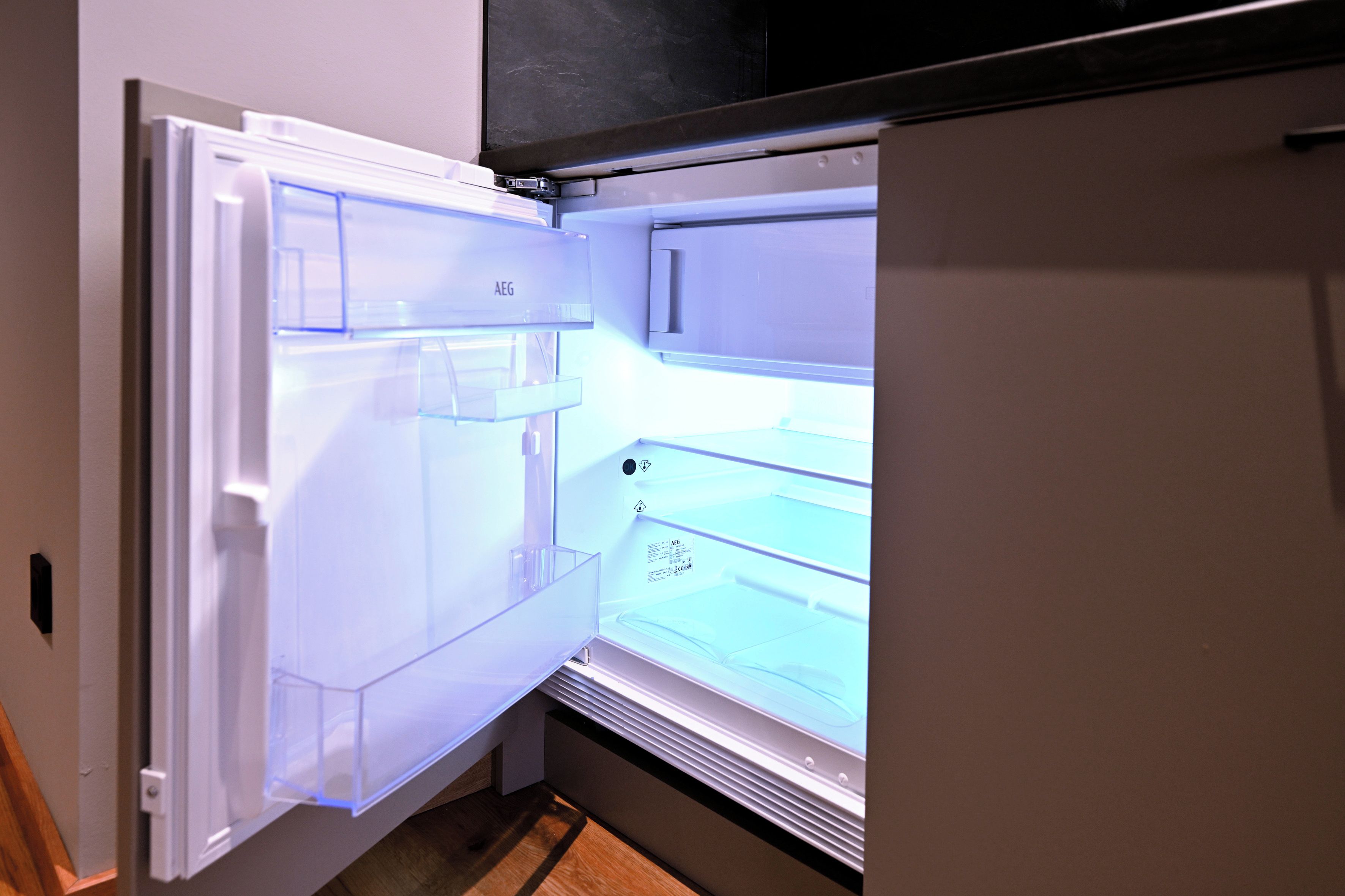 Un réfrigérateur ouvert, doté d’une porte transparente qui laisse voir les étagères à l’intérieur.